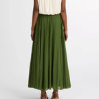 Person wearing a white sleeveless top and green skirt on a white background