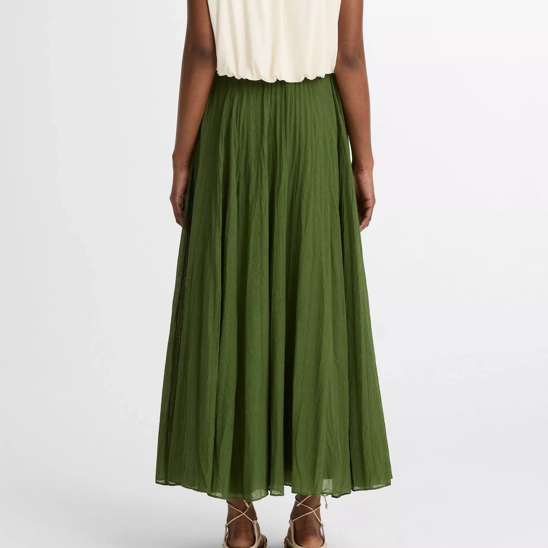 Person wearing a white sleeveless top and green skirt on a white background