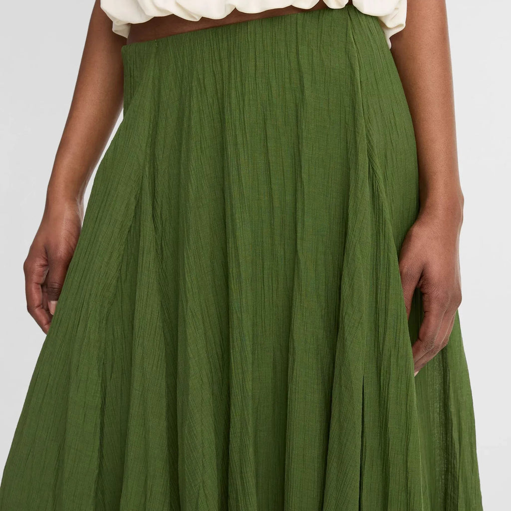 Green skirt worn with a white top on a plain background