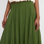 Green skirt worn with a white top on a plain background