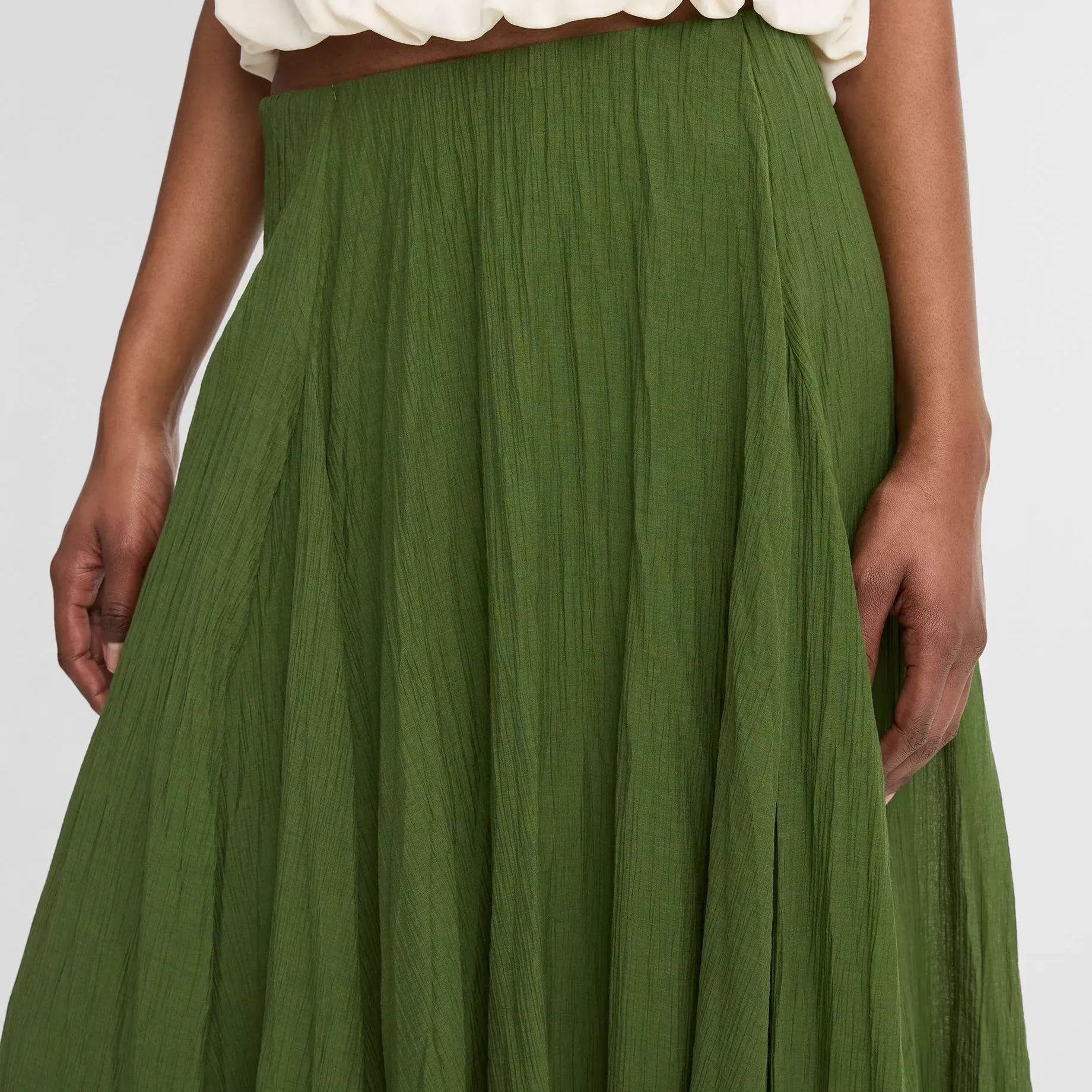 Green skirt worn with a white top on a plain background