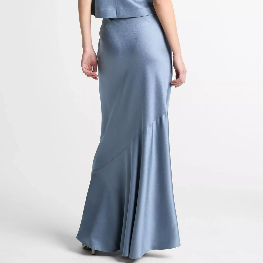 A model shown from the back wearing a sleeveless cream jumpsuit with wide-leg trousers and a high waist, set against a plain light gray studio background.