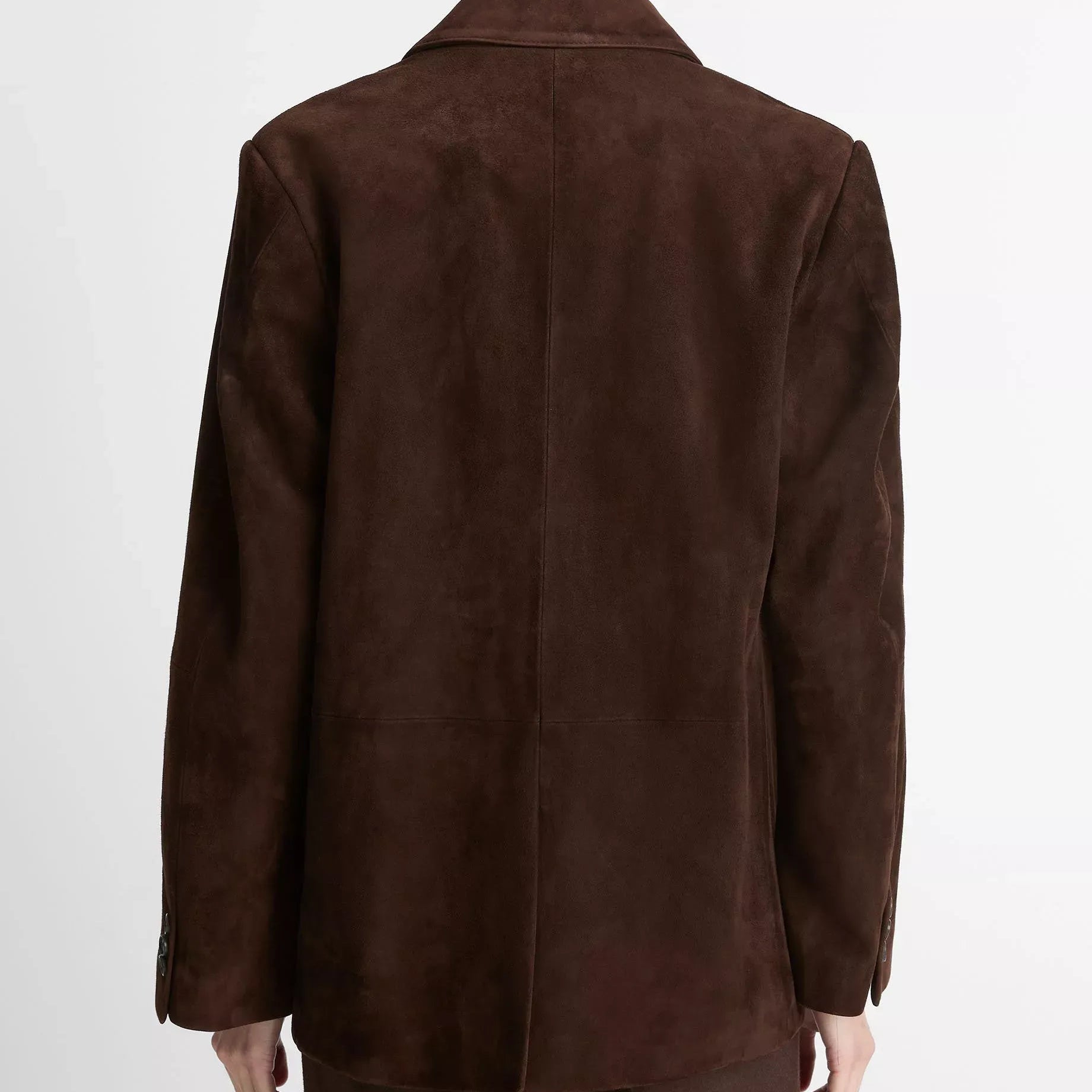 A person shown from the back wearing a dark brown suede blazer and matching dark brown trousers against a plain light gray studio background.