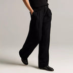 A model wearing a light beige sleeveless top and matching wide-leg trousers with a tie waist, styled with beige heeled sandals against a neutral studio background.