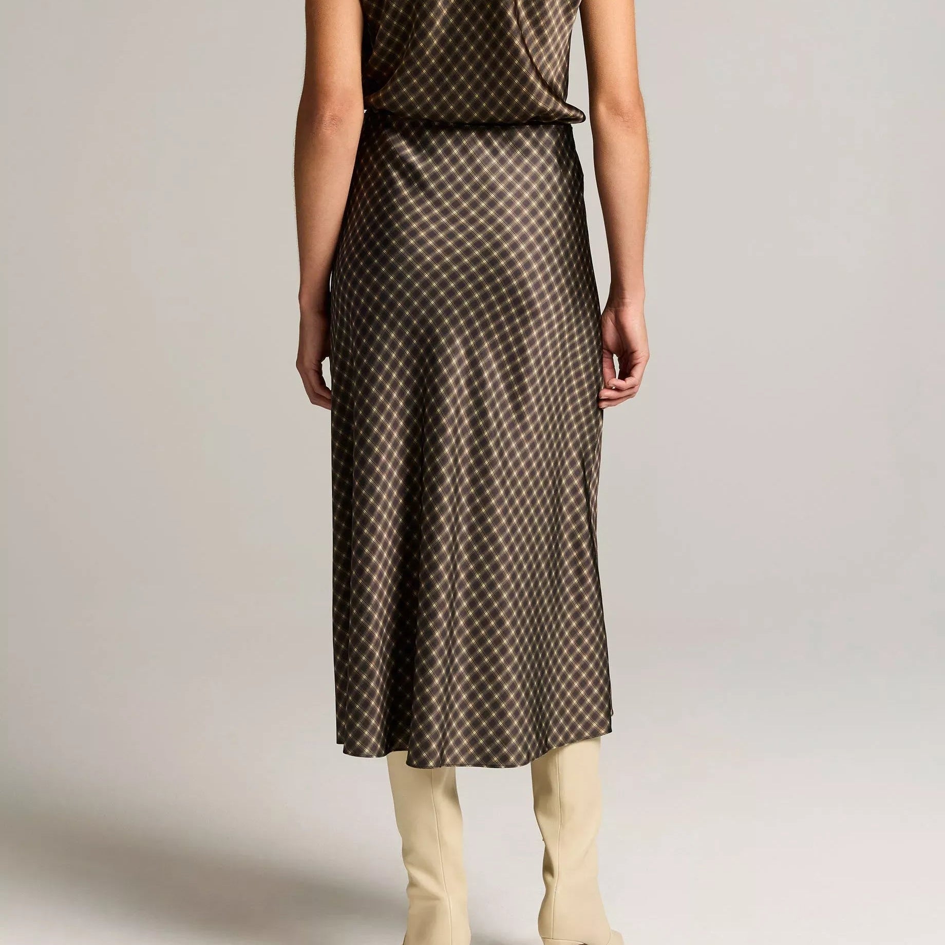 A woman wearing a sleeveless, floor-length satin-like dress in a dusty light blue shade, shown from the back against a plain light gray studio background.
