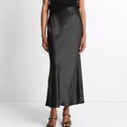 Person wearing a black top and black satin skirt on a white background