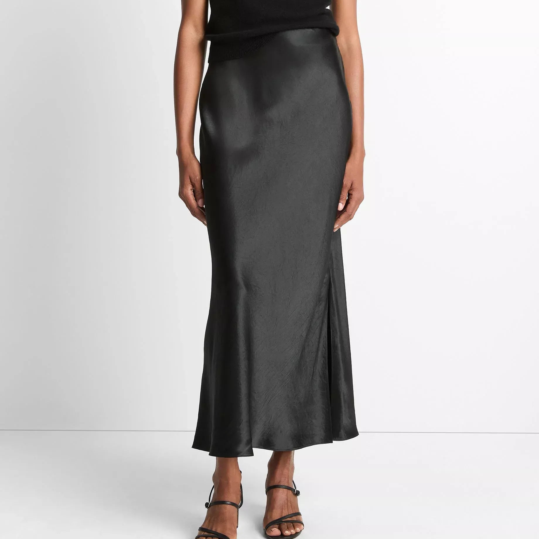 Person wearing a black top and black satin skirt on a white background