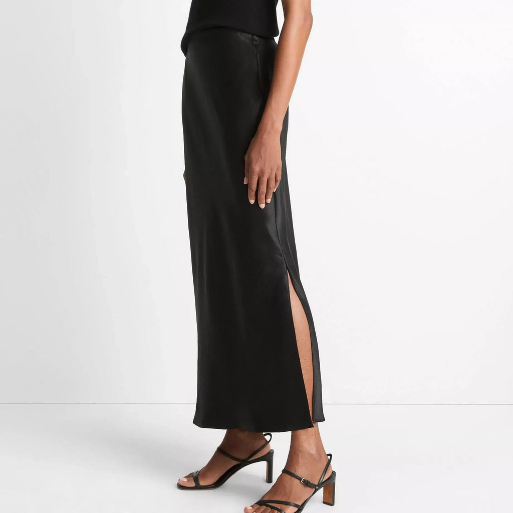 Person wearing a black top and black slip skirt on a white background