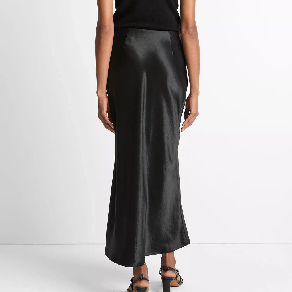 Person wearing a black top and black satin skirt on a white background