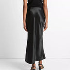 Person wearing a black top and black satin skirt on a white background