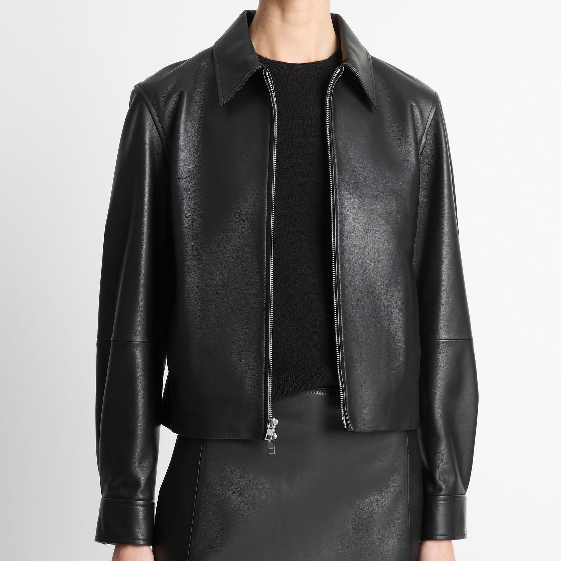 Person wearing a black leather jacket on a plain background