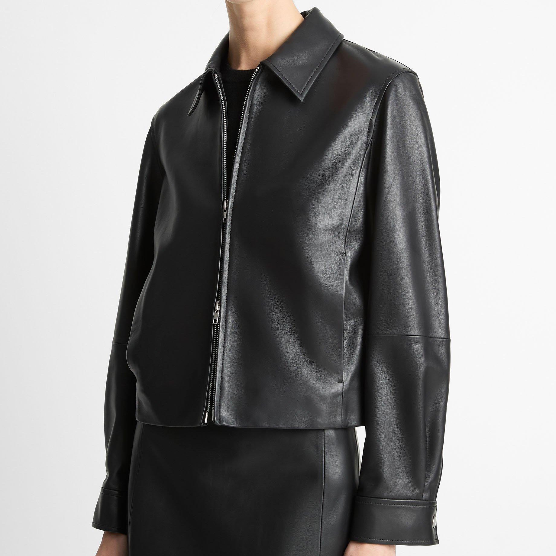 Person wearing a black leather jacket on a light gray background