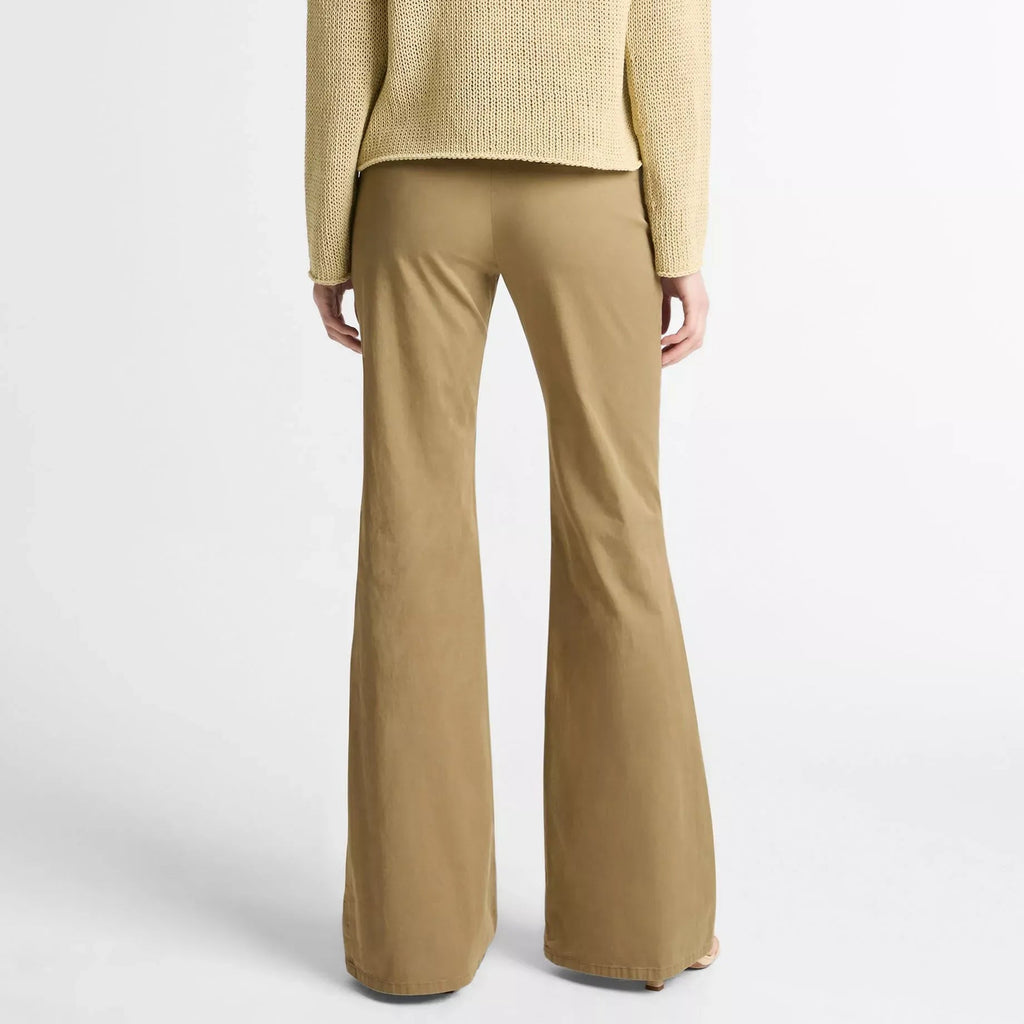 A model shown from the back wearing a textured light beige knit sweater and matching tan wide-leg trousers against a plain light gray studio background.