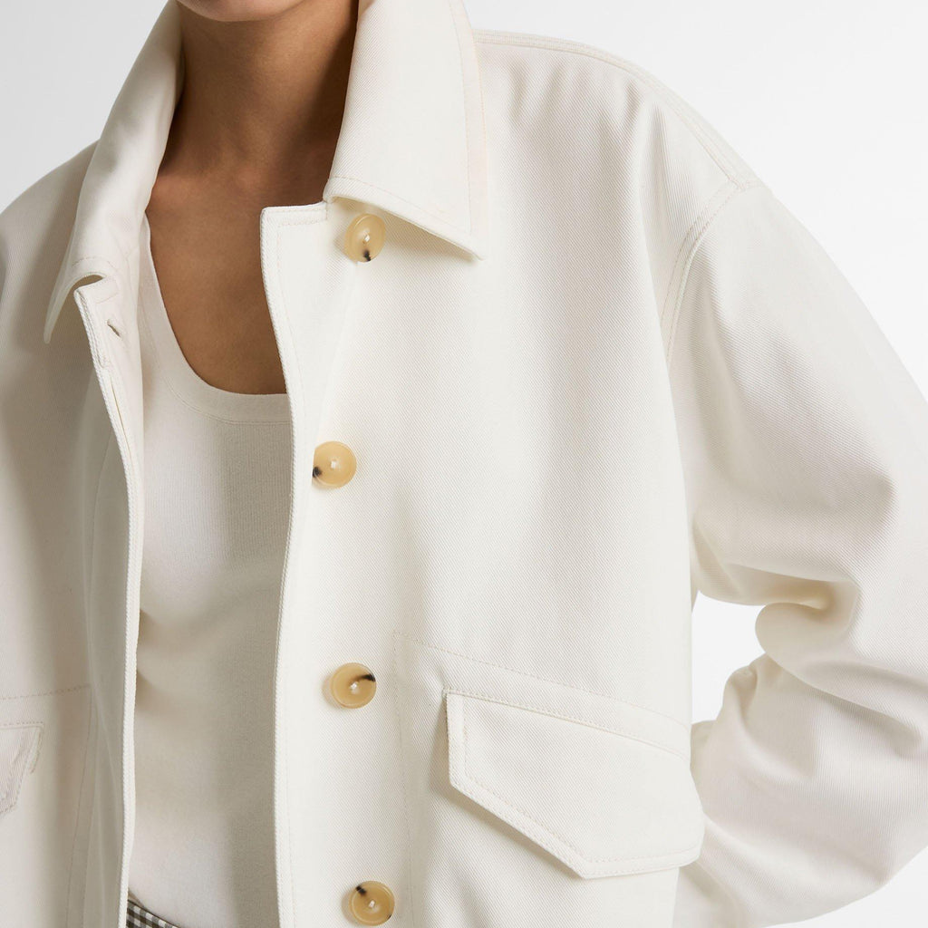 White jacket with gold buttons worn by a person on a white background